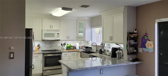 a kitchen with kitchen island granite countertop a sink cabinets and stainless steel appliances
