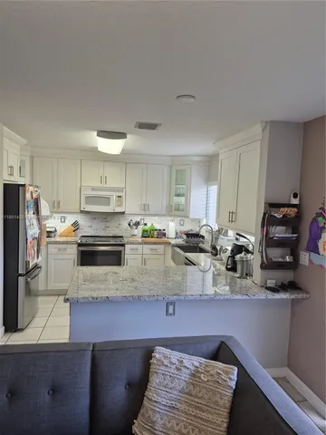 a kitchen with stainless steel appliances granite countertop a sink refrigerator and cabinets