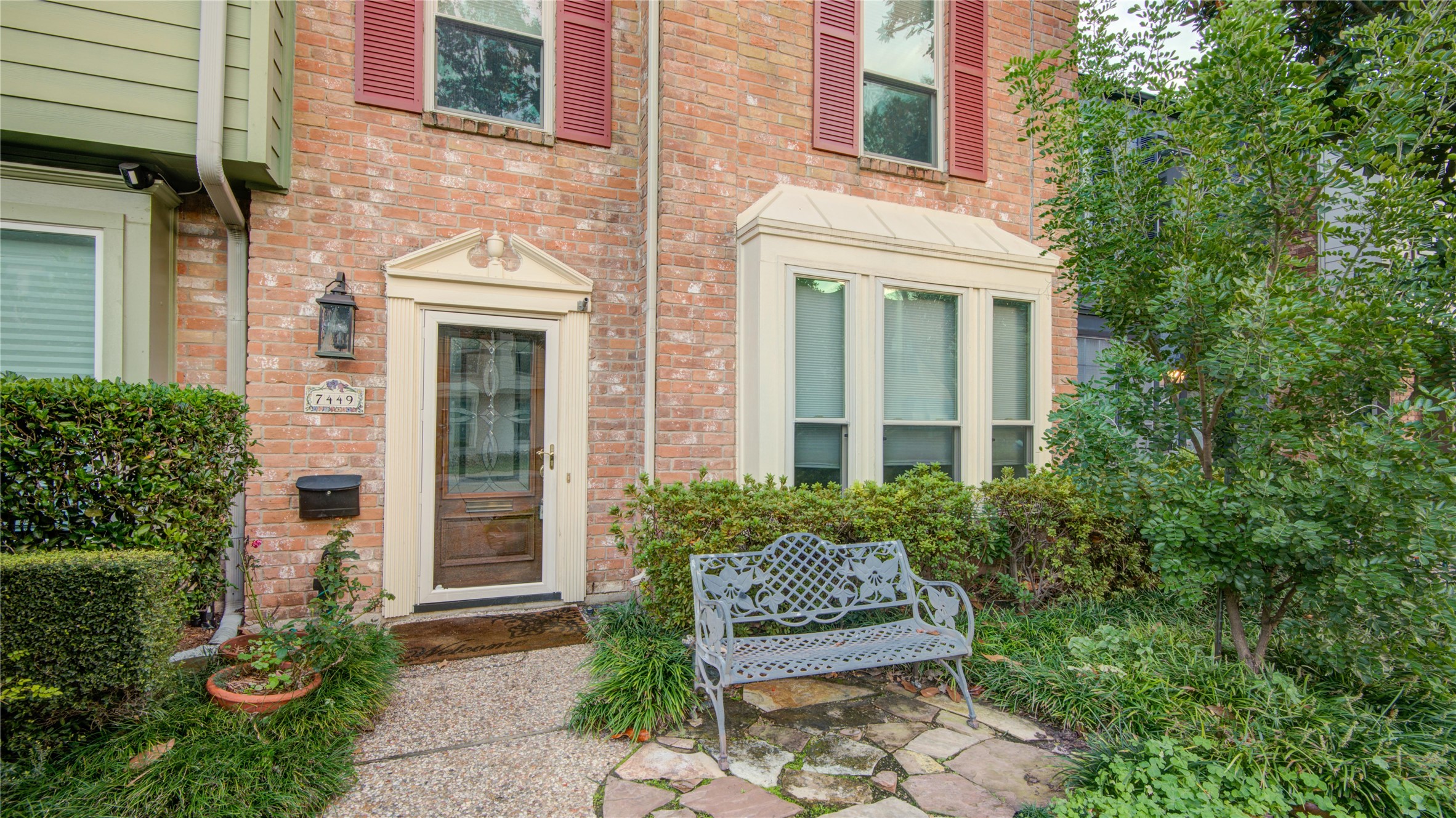 7449 Brompton Street, Unit 7449 Houston, TX 77025 - Photo 5 of 46 a view of a brick house with plants and large windows