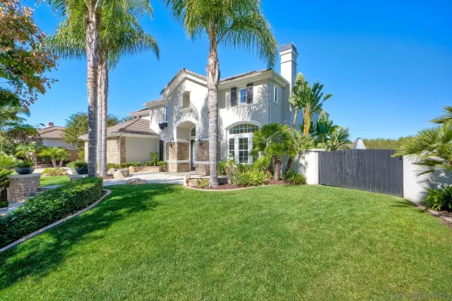 a view of a house with a yard and palm trees