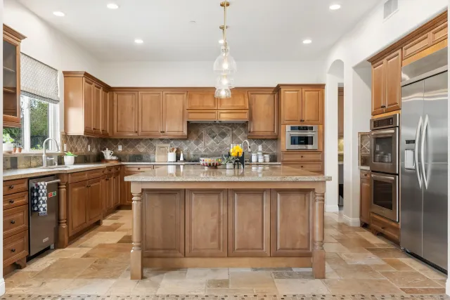 a kitchen with stainless steel appliances granite countertop a refrigerator a sink a stove and cabinets