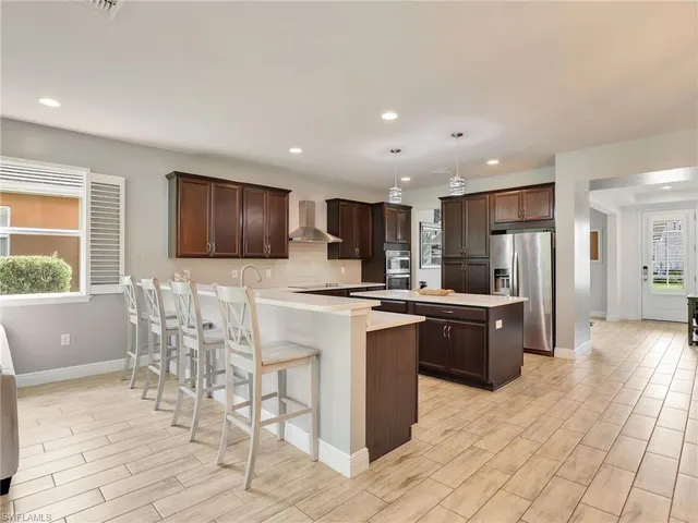 a kitchen with stainless steel appliances granite countertop a stove top oven a sink dishwasher a dining table and chairs with wooden floor