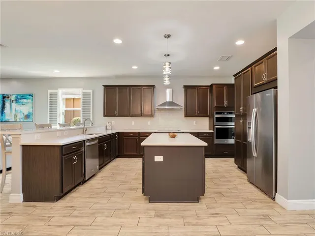 a kitchen with stainless steel appliances granite countertop a stove a sink dishwasher a refrigerator and a oven with wooden floor