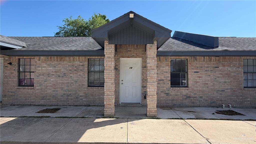 2714 West Mile 17 1/2 Road, Unit 18 Edinburg, TX 78541 - Photo 1 of 11 View of exterior entry with a patio area, brick siding, and roof with shingles
