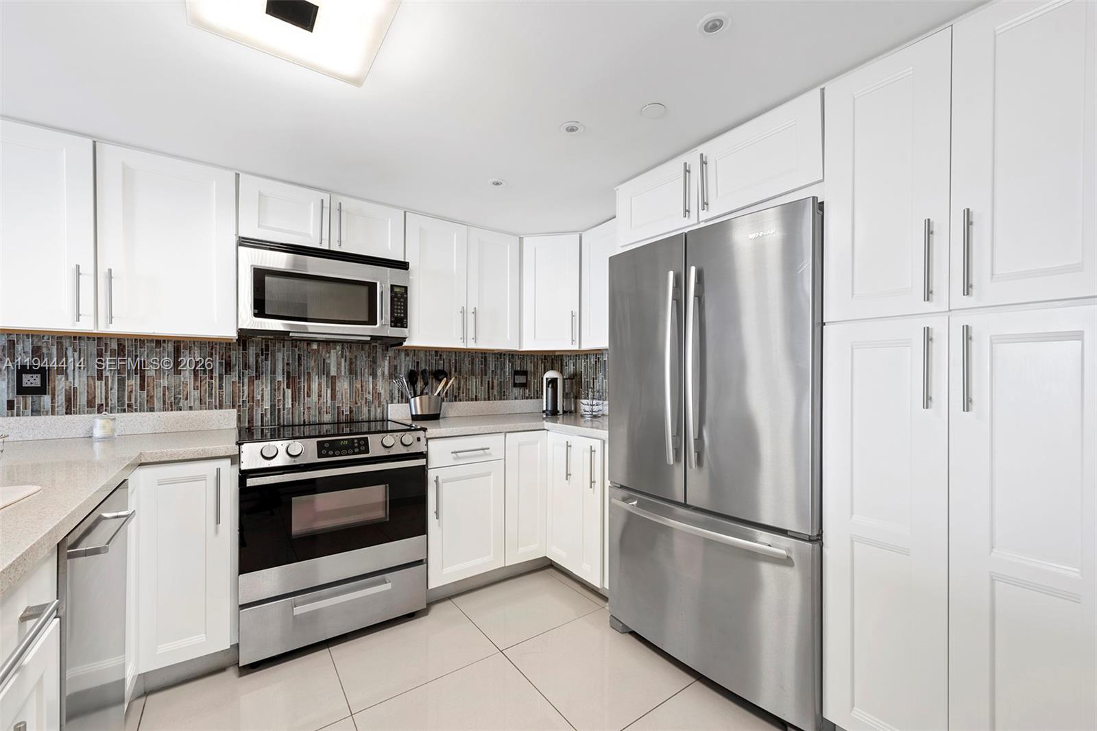 555 Northeast 15th Street, Unit 26B Miami, FL 33132 - Photo 7 of 18 a kitchen with white cabinets and stainless steel appliances