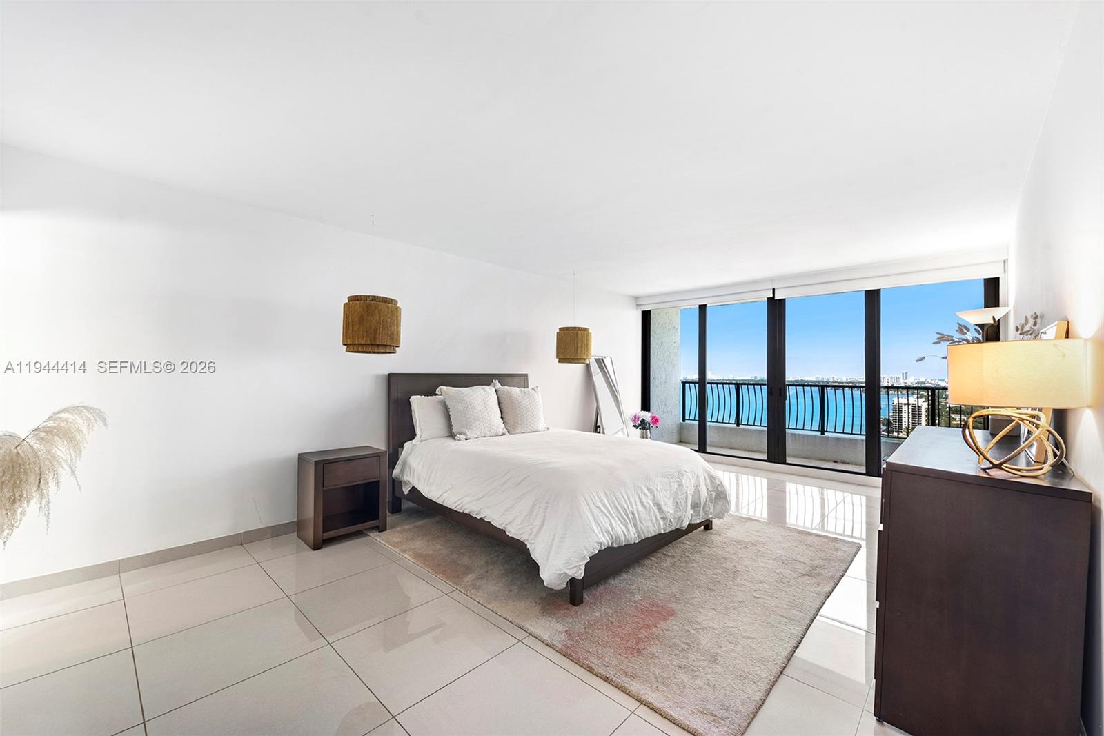 555 Northeast 15th Street, Unit 26B Miami, FL 33132 - Photo 10 of 18 a bedroom with a bed a mirror and lamp next to a window