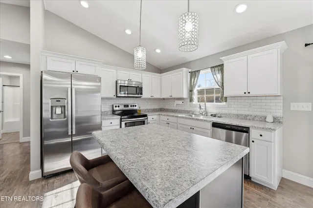 a kitchen with stainless steel appliances granite countertop a sink a stove a refrigerator cabinets and a counter top space