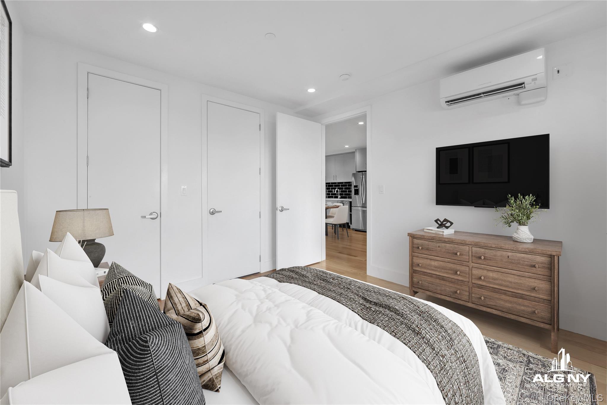 63-34 Fresh Pond Road, Unit 3G Queens, NY 11385 - Photo 2 of 6 a bedroom with a bed and a flat screen tv in white walls