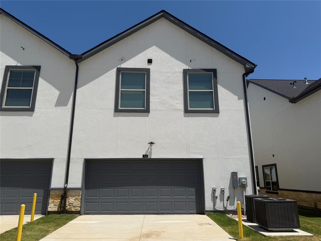 313 Buck Ridge Drive Frisco, TX 75068 - Photo 20 of 20 Modern architectural design featuring a two-car garage with a concrete driveway, stucco exterior, dark trim accents, and a stone foundation detail