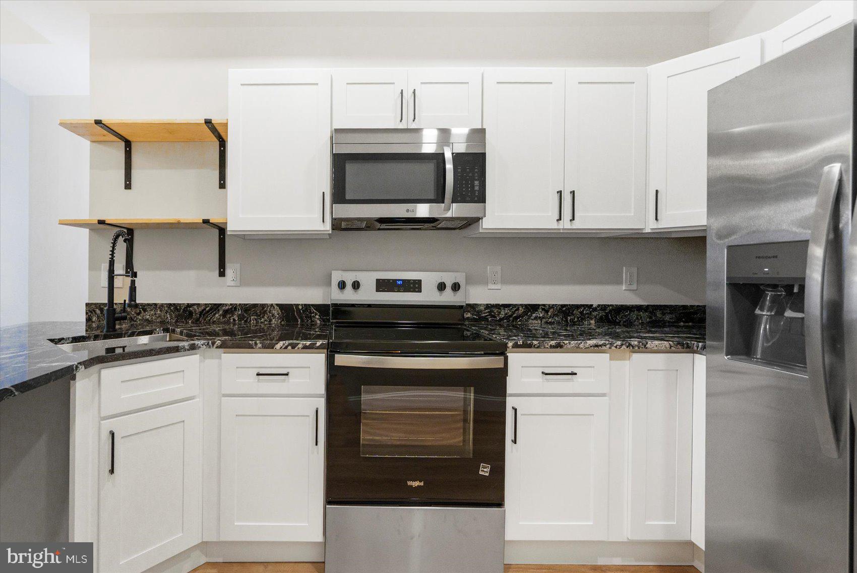 1415 East Lanvale Street Baltimore, MD 21213 - Photo 12 of 42 a kitchen with stainless steel appliances granite countertop a stove a sink and a microwave