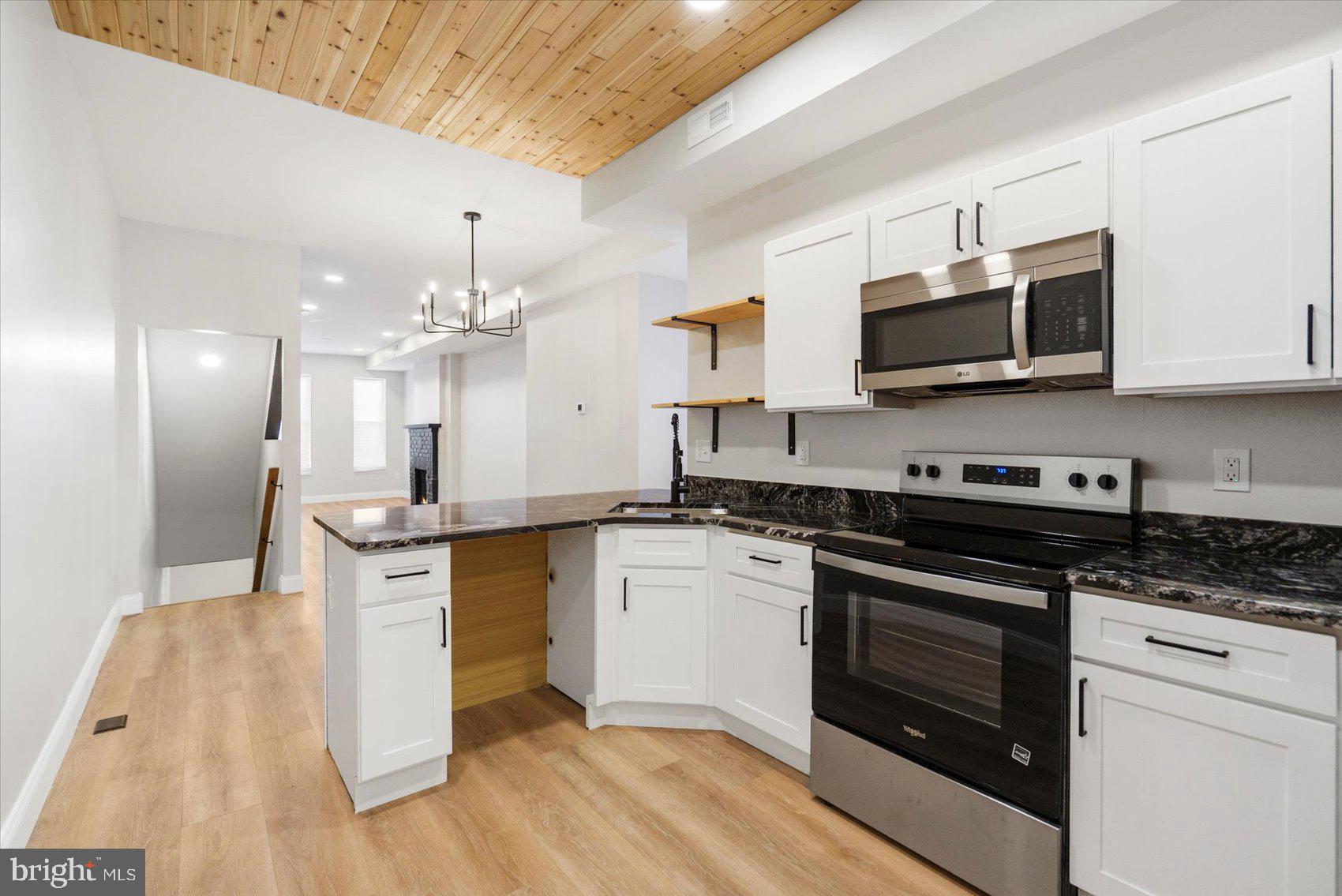 1415 East Lanvale Street Baltimore, MD 21213 - Photo 16 of 42 a kitchen with stainless steel appliances kitchen island granite countertop a stove a sink and a microwave