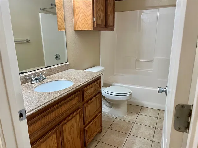 a view of an empty room with window and chandelier fan
