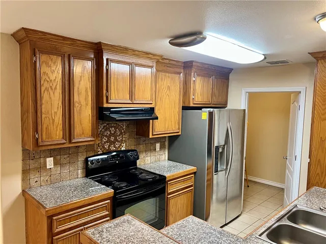 a kitchen with stainless steel appliances granite countertop a refrigerator and a stove top oven