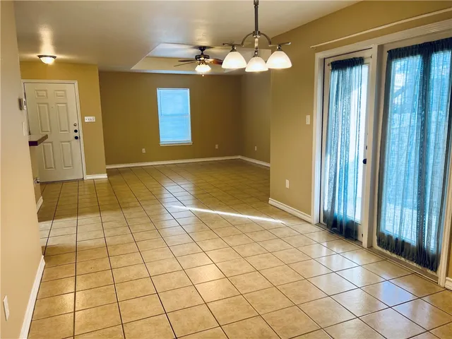 an empty room with kitchen and chandelier fan