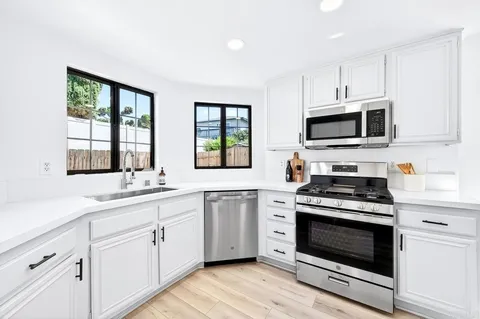 a kitchen with cabinets stainless steel appliances and wooden floor