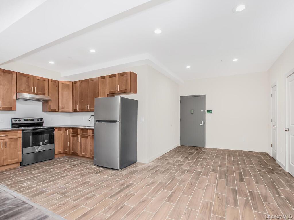 409 Warburton Avenue, Unit 5A Yonkers, NY 10701 - Photo 2 of 13 Kitchen featuring appliances with stainless steel finishes, brown cabinetry, recessed lighting, wood finish floors, and under cabinet range hood