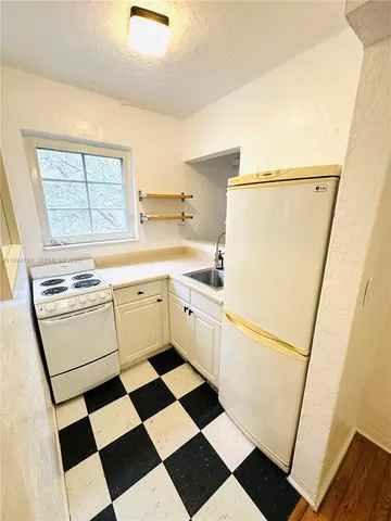 a kitchen with a refrigerator a sink and white cabinets