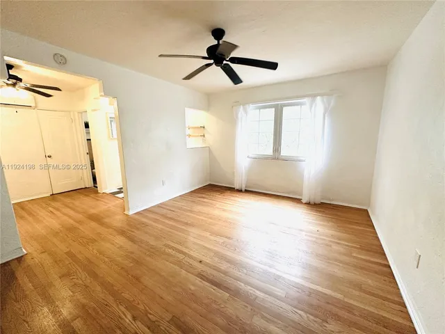 a view of empty room with wooden floor and ceiling fan