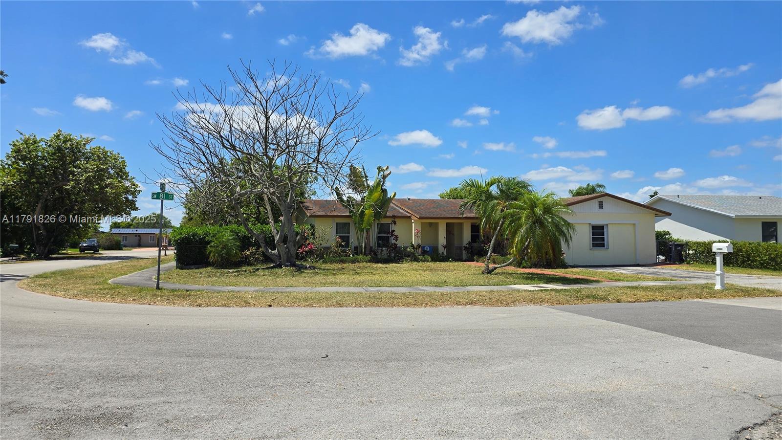 a view of a house with a big yard and palm trees