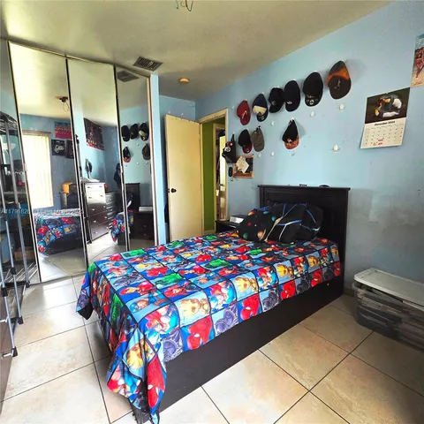 a bedroom with a bed a dresser and a lamp