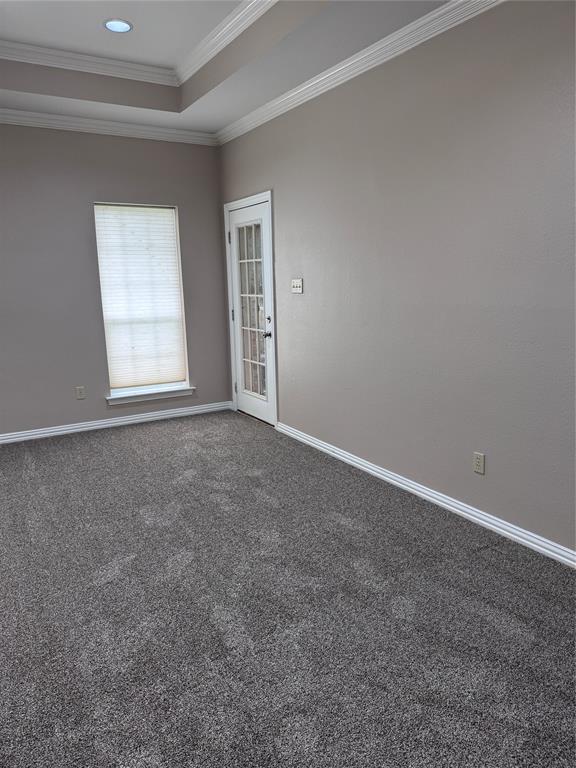 1704 South Bowen Road Pantego, TX 76013 - Photo 14 of 37 Spacious primary,ADA compliant bedroom featuring tray ceiling with recessed lighting, plush grey carpeting, and a glass-paned door which opens to the backyard