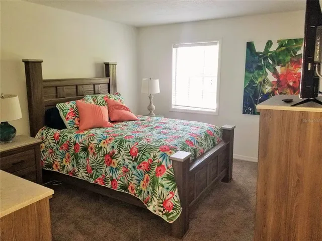a bedroom with a bed painting on the wall and a window