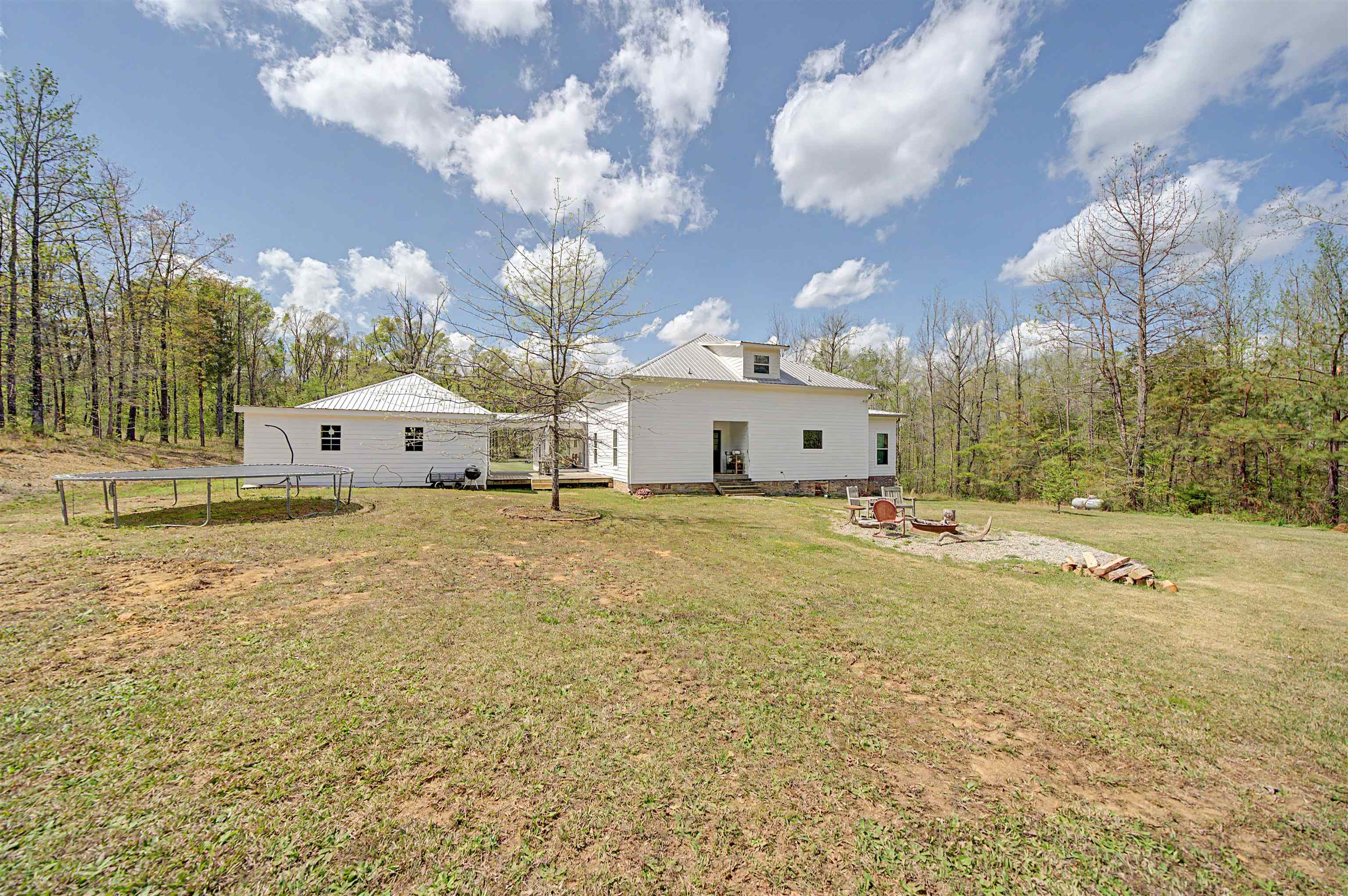 300 Grace Thomas Road Michie, TN 38357 - Photo 23 of 26 Rear view of property featuring a trampoline, a fire pit, a yard, and a patio area