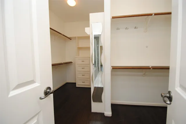 a bedroom with a bed a mirror on dresser and a window