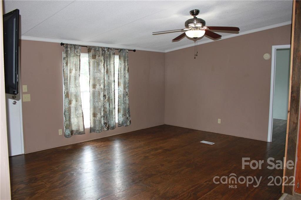 339 Dewitt Owens Road Rutherfordton, NC 28139 - Photo 12 of 48 an empty room with wooden floor chandelier fan and windows