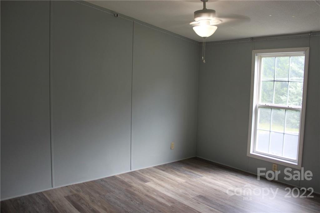 339 Dewitt Owens Road Rutherfordton, NC 28139 - Photo 17 of 48 an empty room with wooden floor a ceiling fan and windows