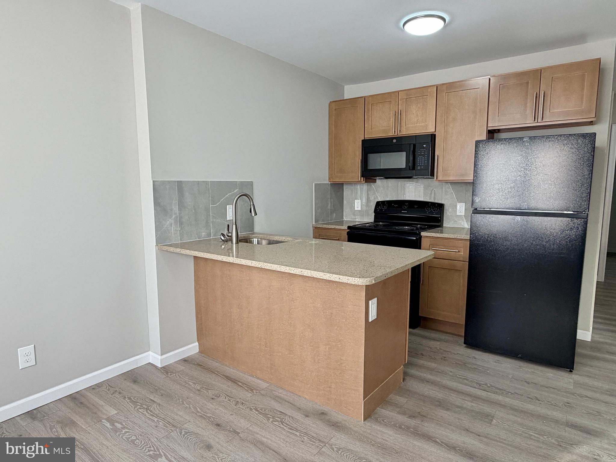 1727 Dallas Street, Unit 1 Philadelphia, PA 19126 - Photo 5 of 25 a kitchen with a sink a refrigerator a microwave and cabinets