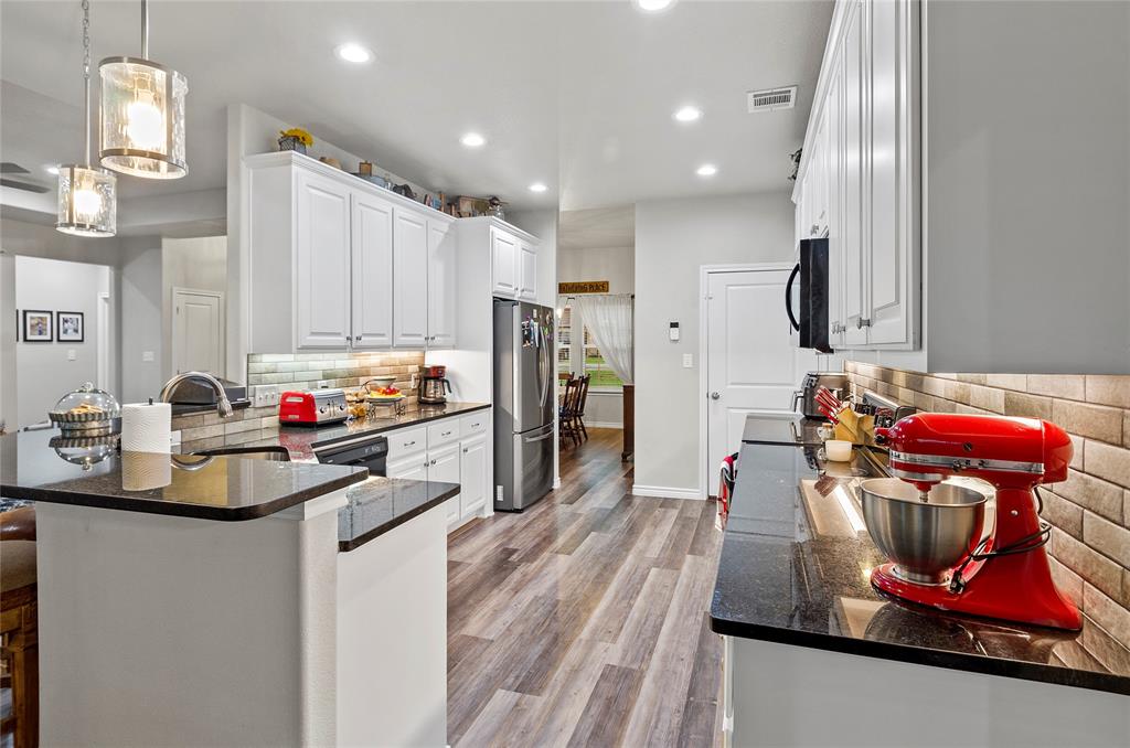 141 Walnut Street Paradise, TX 76073 - Photo 12 of 23 Kitchen featuring backsplash, a peninsula, white cabinets, and dark stone countertops