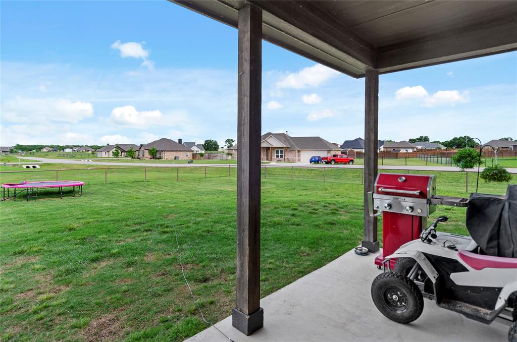 141 Walnut Street Paradise, TX 76073 - Photo 9 of 23 Fenced backyard featuring a residential view, a trampoline, and a patio