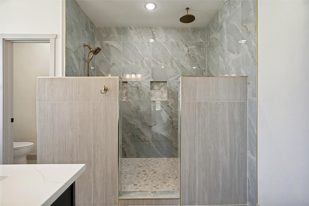 1150 Doss Road Millsap, TX 76066 - Photo 23 of 32 Walk-in shower featuring jaw stopping marbled tile walls, a pebbled floor, and dual shower heads.