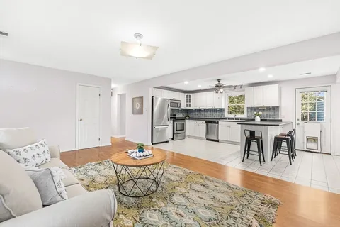 a living room with furniture kitchen view and a wooden floor