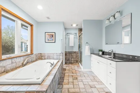 a spacious bathroom with a granite countertop tub sink and mirror