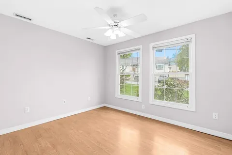 an empty room with windows and ceiling fan