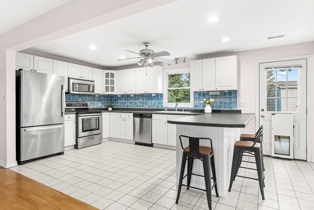 3 Theresa Road Stoneham, MA 02180 - Photo 5 of 42 a kitchen with stainless steel appliances kitchen island granite countertop a refrigerator a stove a sink dishwasher and white cabinets with wooden floor
