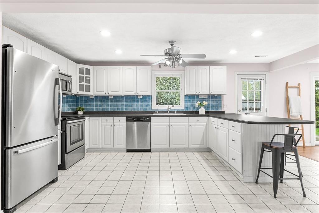 3 Theresa Road Stoneham, MA 02180 - Photo 7 of 42 a kitchen with stainless steel appliances granite countertop a stove a sink dishwasher a refrigerator and white cabinets with wooden floor