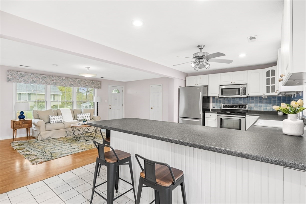 3 Theresa Road Stoneham, MA 02180 - Photo 10 of 42 a kitchen with stainless steel appliances granite countertop a stove top oven a sink a dining table and chairs with wooden floor