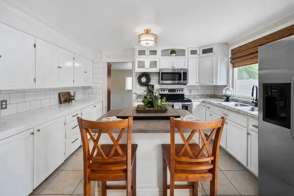 a kitchen with stainless steel appliances a table and chairs in it