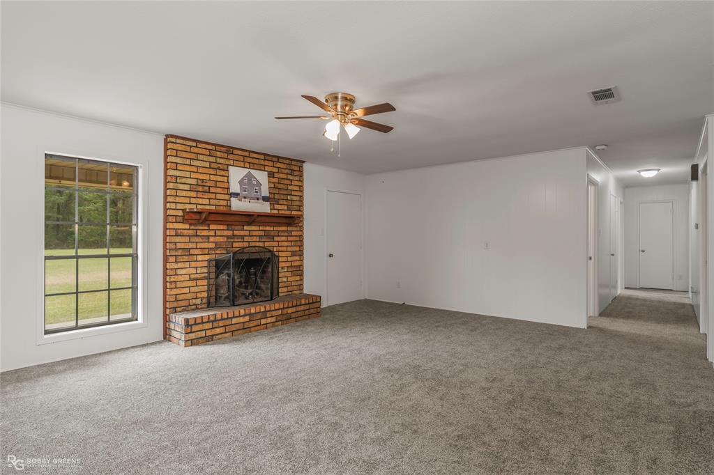 1303 Young Road Benton, LA 71006 - Photo 8 of 34 Unfurnished living room featuring carpet, ceiling fan, and a brick fireplace