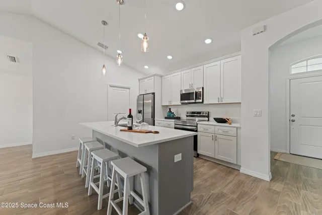 a kitchen with a sink a stove a refrigerator and white cabinets with wooden floor