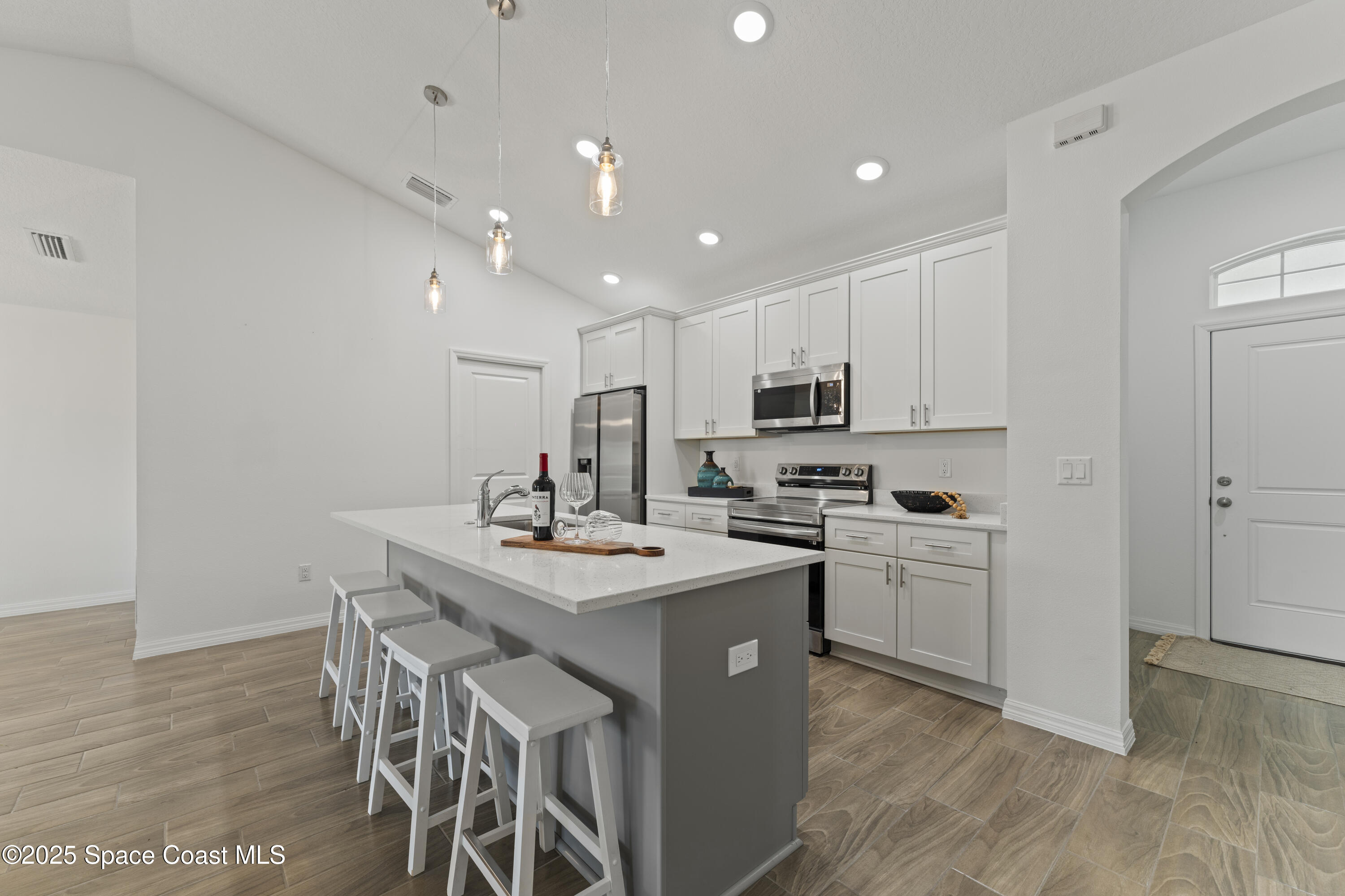 1938 Jupiter Boulevard Southwest Palm Bay, FL 32908 - Photo 5 of 21 a kitchen with a sink a stove a refrigerator and white cabinets with wooden floor