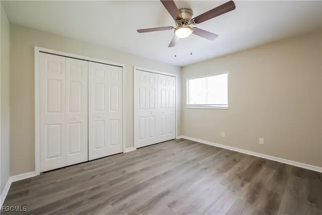 an empty room with wooden floor ceiling fan and windows