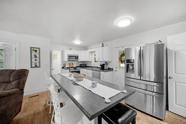 a kitchen with stainless steel appliances granite countertop a stove top oven a sink dishwasher and a refrigerator with wooden floor