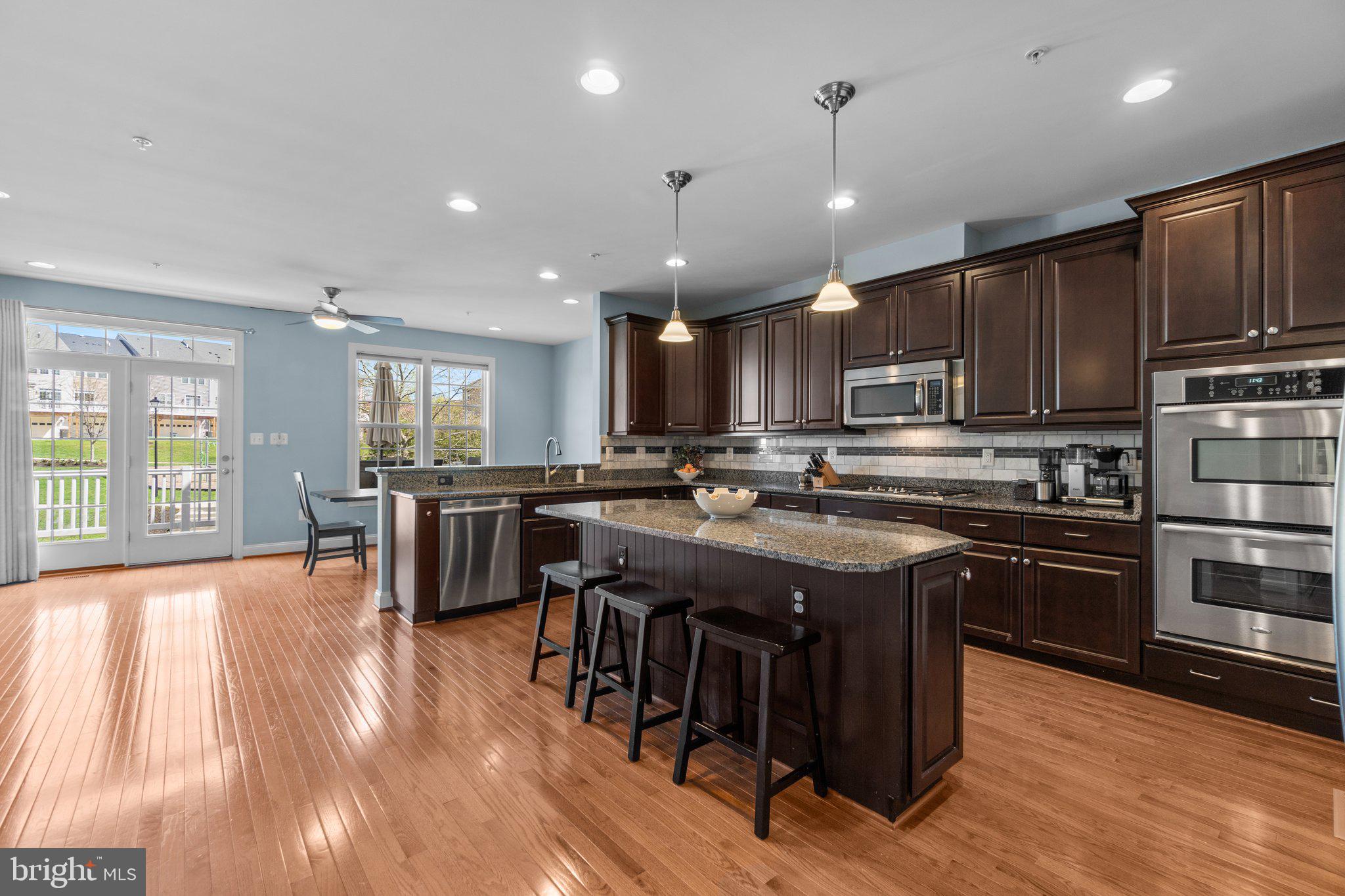 9644 Bothwell Lane Frederick, MD 21704 - Photo 10 of 68 a kitchen with kitchen island granite countertop wooden floors and stainless steel appliances