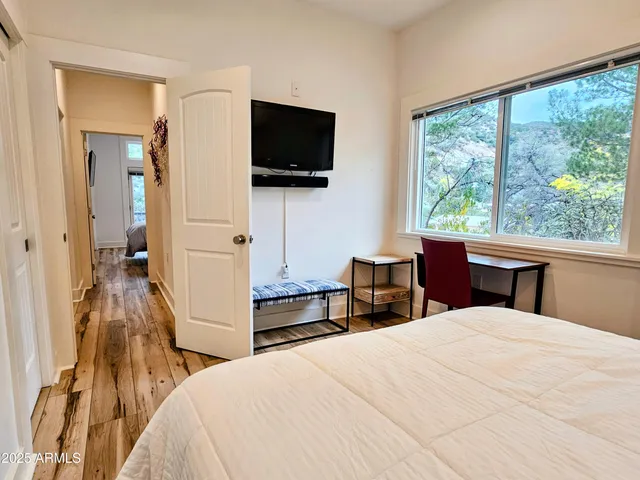 a bedroom with a bed and a flat tv screen on wall