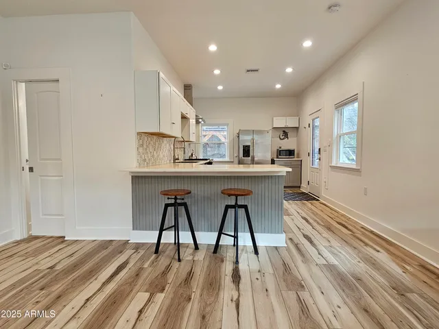 a living room with stainless steel appliances granite countertop furniture wooden floor and a kitchen view