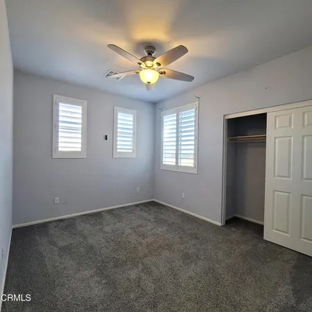 a view of an empty room with window and chandelier fan